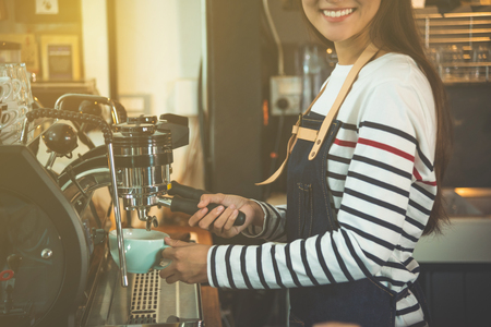 Asian barista making coffee by coffee maker machine with smileの写真素材