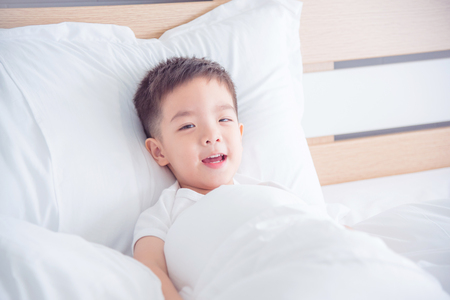 Happy boy smiling on bedの写真素材