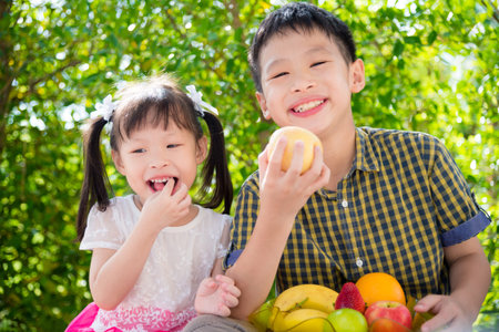 Children eating fruit in parkの写真素材