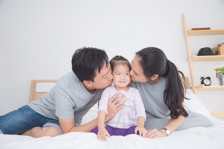 Asian parents kissing their daughterの写真素材