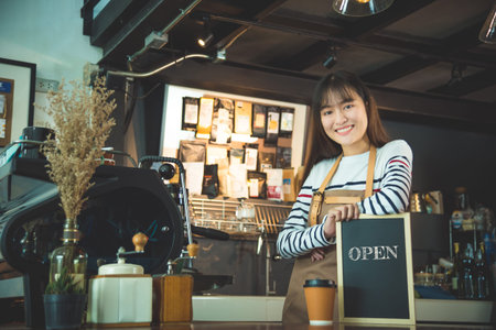 Beautiful barista holding blackboard with wordopen and smiles