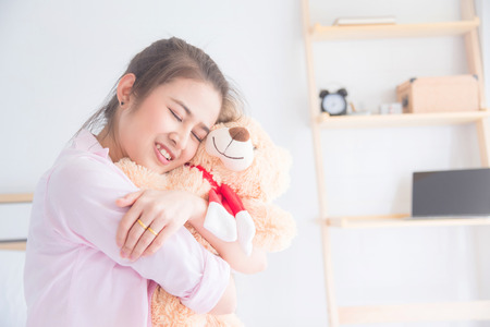 Young beautiful asian woman hugging teddy bear and smilesの写真素材