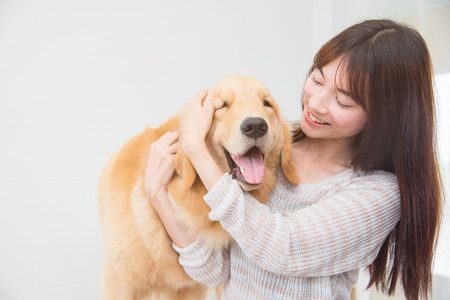 Asian beautiful woman playing with her dog and smiles at homeの写真素材