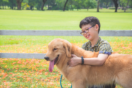 Young asian boy sitting and talking with his dog in parkの写真素材