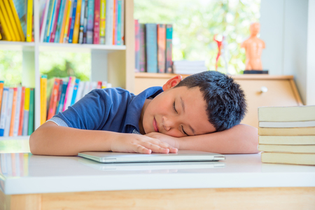Young asian schoolboy fall asleep in school libraryの写真素材