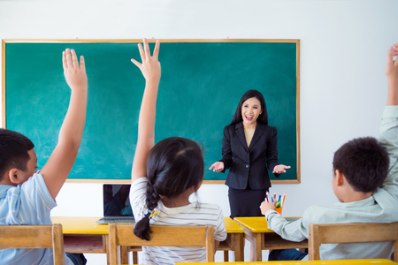 Beautiful asian teacher teaching students in classroom