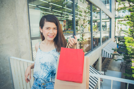 Beautiful asian woman holding many shopping bags and smiles