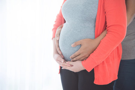 Pregnant woman belly with hands of husband holding from back side