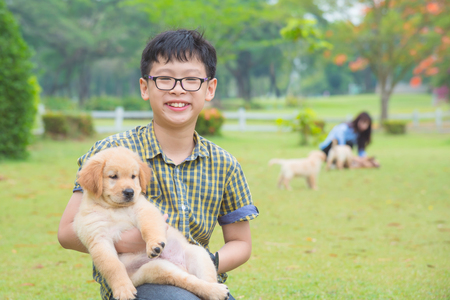 Young asian boy holding his dog and smiles in parkの写真素材