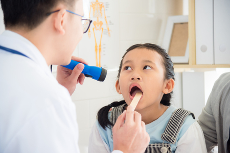 Young asian girl open her mouth for doctor doing oral examinationの写真素材