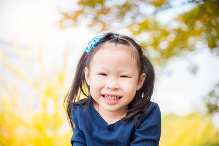Little asian girl smiling in autumn parkの写真素材