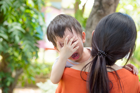 Little asian boy crying while mother holding him to go to schoolの写真素材