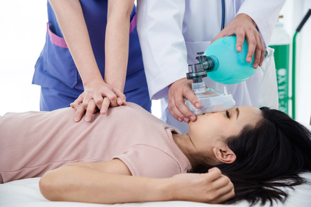 Hands of doctors giving cardiac massage and resuscitation to a female patient in the emergency roomの写真素材