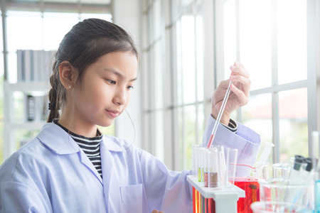 Young asian school girl doing experiment in chemistry classroomの写真素材