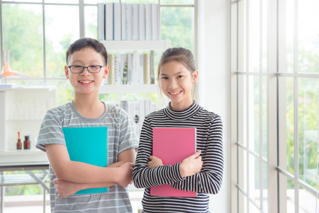 Young asian boy and girl standing and smiling in classroomの写真素材
