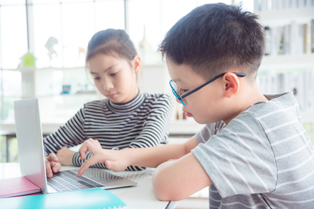 Young asian children using notebook computer at school library,education concept.の写真素材