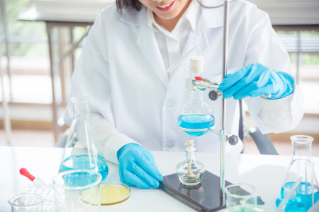 Scientist doing experiment in lab,many glassware on table.