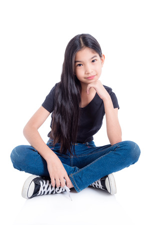 Full length of asian girl sitting and smiles on floor over white backgroundの写真素材