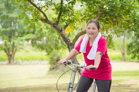 Beautiful aged asian woman riding bicycle for exercise in park,healthcare concept.の写真素材