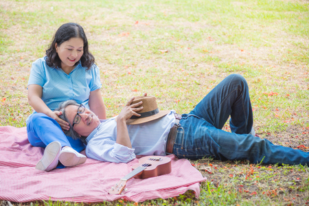 Portrait Of Senior Asian Couple Sitting In Park Togetherの写真素材