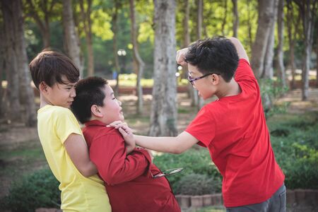 Asian schoolboy getting bullied ,Children fighting with classmate in school park. Bullying and violence in school concept.の写真素材