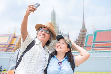 Asian senior couple taking their photo by smartphone while traveling in Bangkok,Thailand. Happy retirement concept.の写真素材