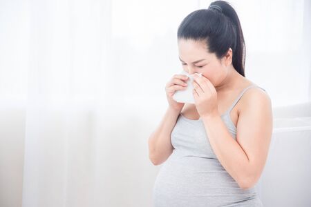 Pregnant woman wipe her nose by tissue paper. Pregnancy health and medicine concept.の写真素材