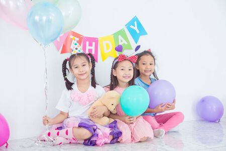 Colorful portrait of three happy asian girls sitting together in celebration of birthday and smiling.の写真素材