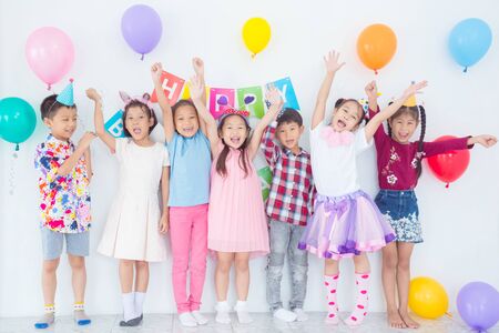 Colorful portrait of seven happy asian kids standing together in celebration of birthday and smiling.の写真素材