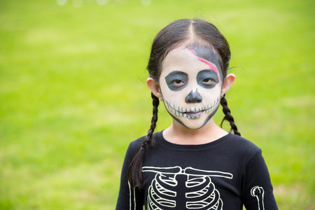 Little asian girl in bone devil costume celebrate Halloween outdoor.の写真素材