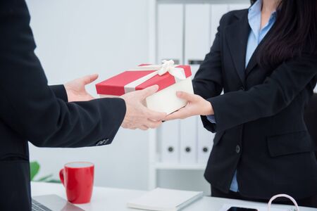 Hands of businesswoman giving christmas gift to her boss in office.の写真素材