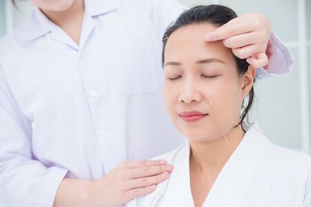 Beautiful asian woman receiving facial acupuncture treatment at clinic Alternative medicine concept.の写真素材