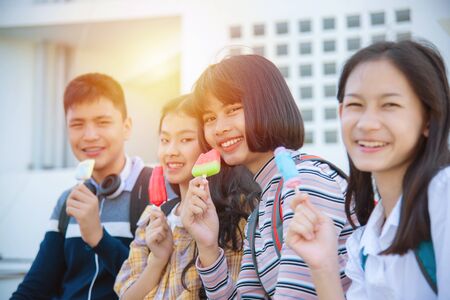 Beautiful asian teenage woman sitting and eating ice-cream with friends.の写真素材