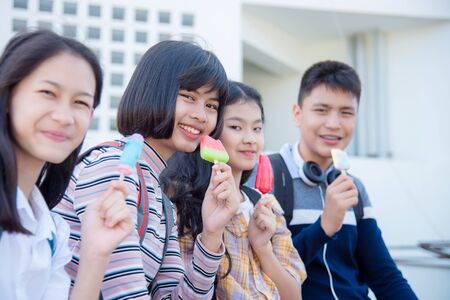 Beautiful asian teenage woman sitting and eating ice-cream with friends.の写真素材