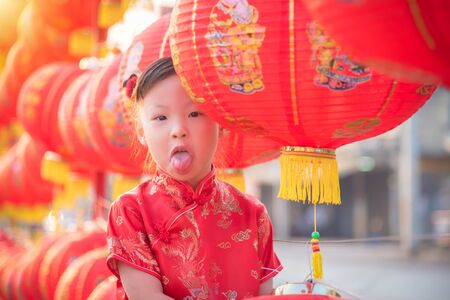 Little asian girl wearing chinese treditional costume standing with red lantern in chinese new year festival.の写真素材