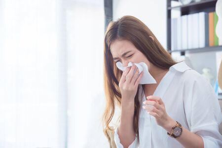 Young asian beautiful woman having running nose,wipe her nose by tissue paper.の写真素材