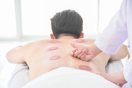 Therapist doing Tui na massage for her patient after cupping therapy finished ,Chinese alternative medicine.の写真素材