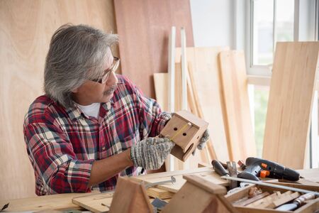 Senior Asian male carpenter working woodwork at carpentry shop.の写真素材