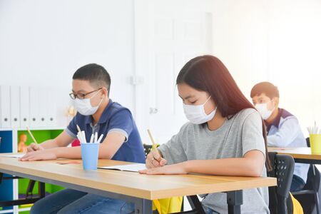 Group of young asian students wearing facial mask sitting and studying in classroom .の写真素材