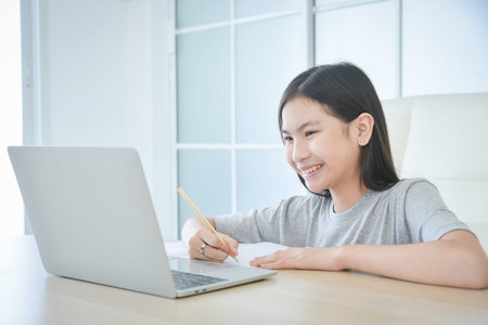 Preteen asian schoolgirl online learning with laptop at home. Education and distance learning for...