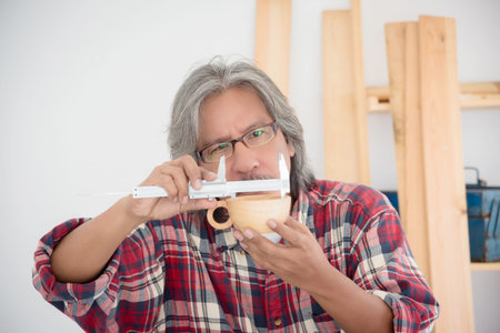 Senior Asian male carpenter working woodwork at carpentry shop.の写真素材