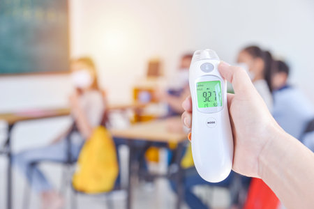 Digital thermometer, thermometer gun on teacher hand using for check body temperature of students...