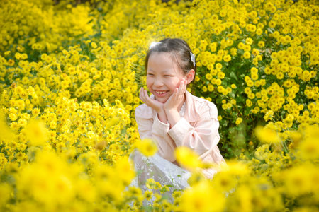 Young beautiful asian girl child sitting  and smiles in yellow Chrysanthemum field.