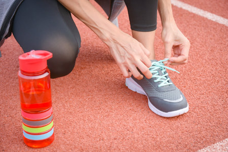 Sporty woman tying her shoelaces before jogging outdoor in the city.