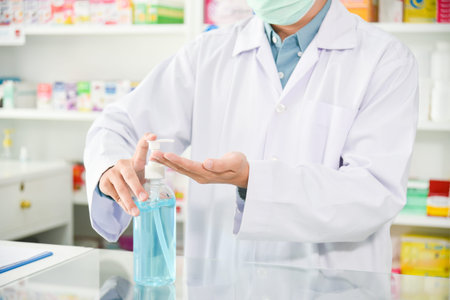 Pharmacist pumping alcohol gel from bottle for washing hand at drugstore.の写真素材