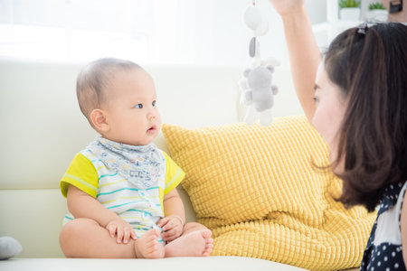 Little asian boy looking at toy that his mother showing in front of him.の写真素材