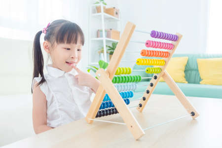 Pretty asian girl counting wood on abacus at home. Child education concept.の写真素材