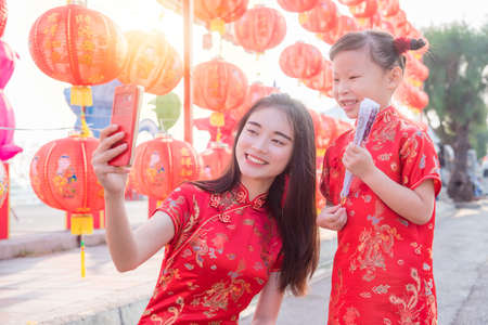 Chinese woman and child wearing traditional dress taking their photo by mobile phone,Chinese new year concept.の写真素材