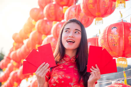 Chinese woman wearing traditional dress holding red envelope with happy face,Chinese new year concept.の写真素材