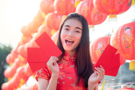 Chinese woman wearing traditional dress holding red envelope with happy face,Chinese new year concept.の写真素材